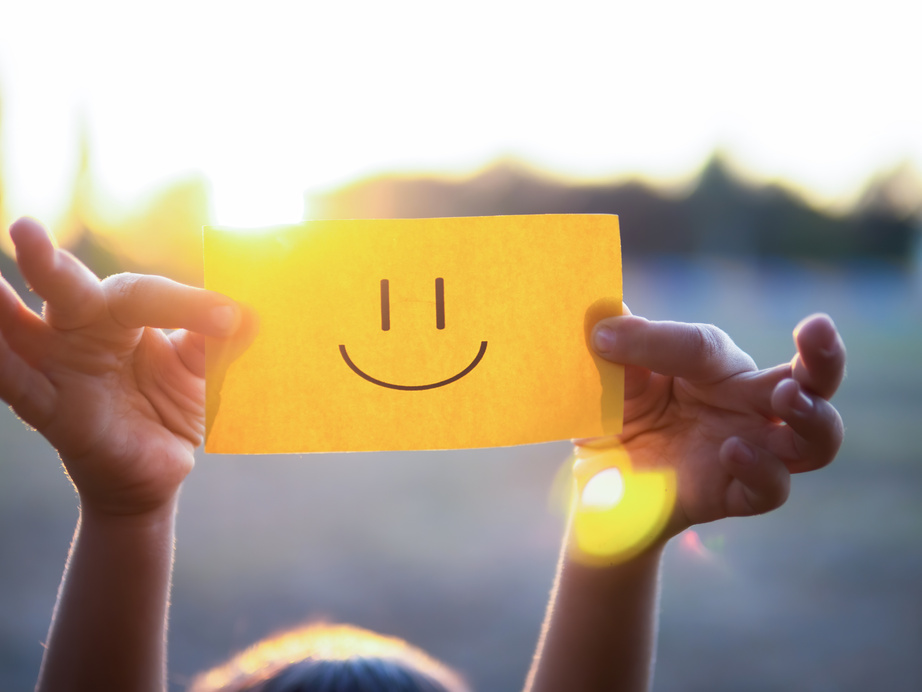 Kid Holding a Yellow Paper with Smiley Against the Sunlight 